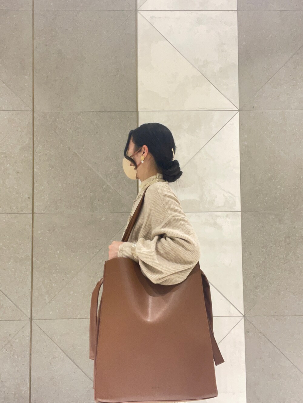 ブラウン系のトートバッグ、ベージュ系のスカート、ベージュ系のカーディガン/ボレロを着用したレディースの春コーディネートの2枚目の写真
