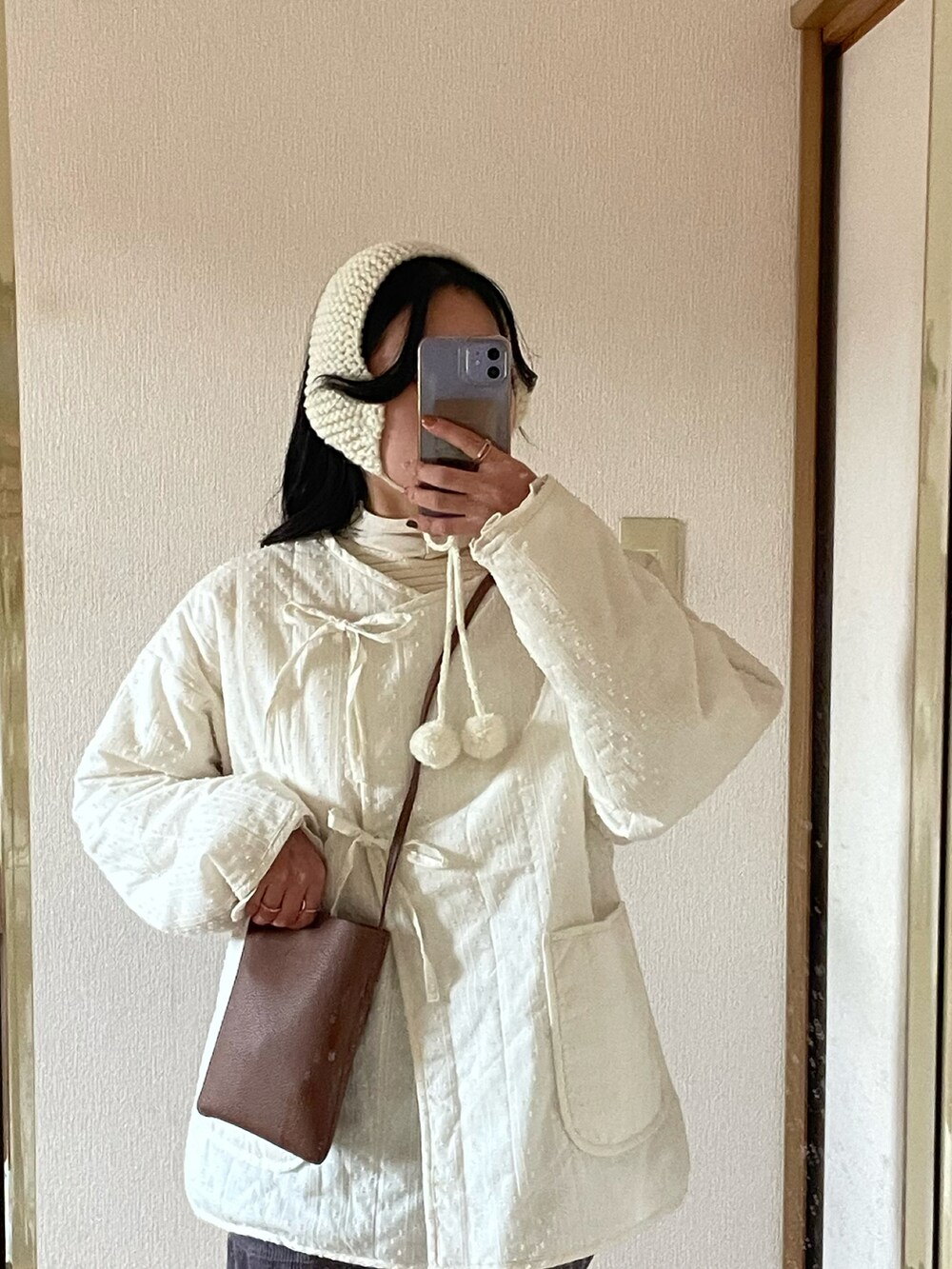 ホワイト系のその他アウター、ホワイト系のその他トップス、ブラウン系のショルダーバッグを着用したレディースの冬コーディネートの2枚目の写真