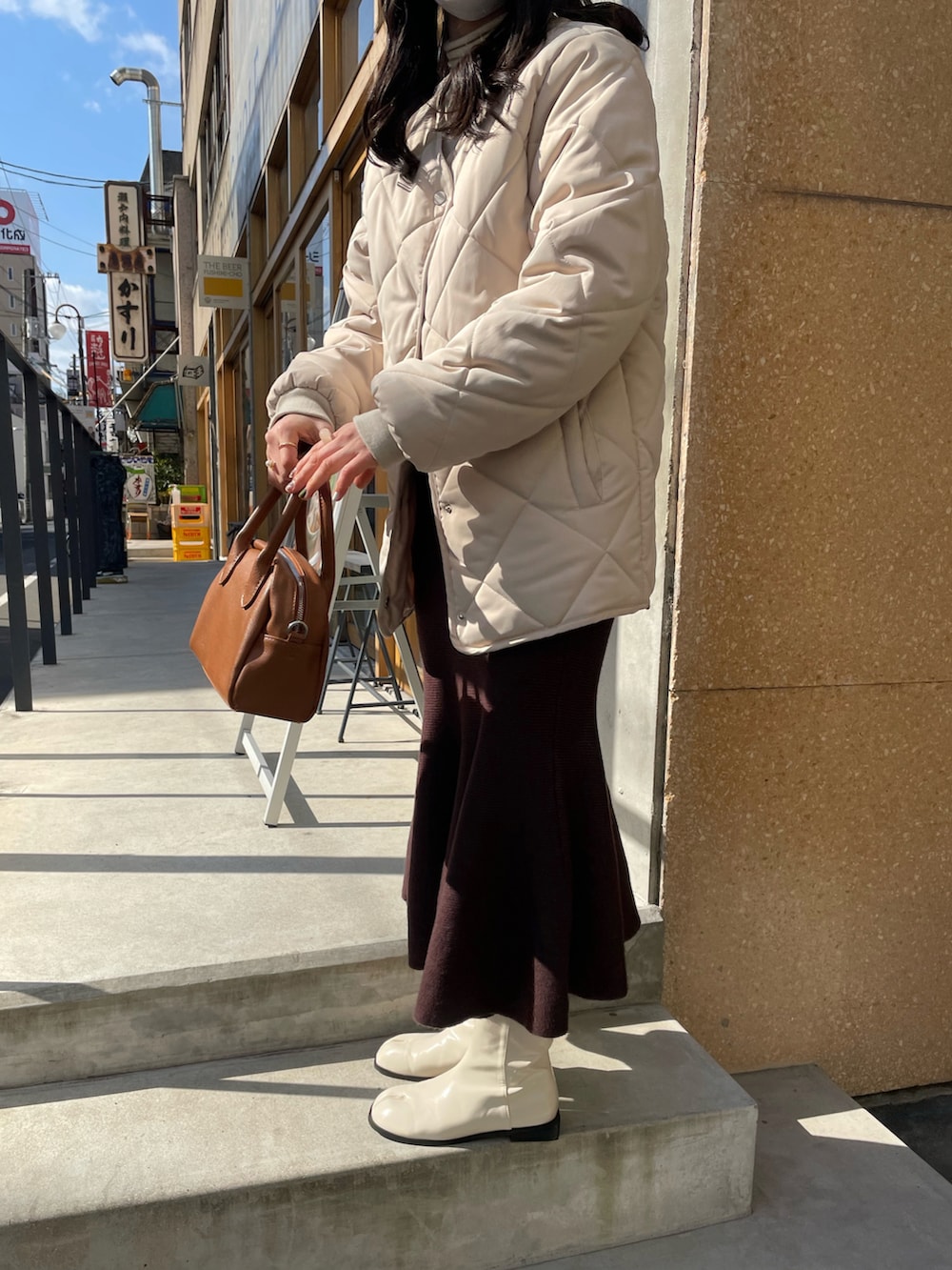 ブラウン系のボストンバッグ、ベージュ系のニット/セーター、ホワイト系のブーツを着用したレディースの冬コーディネートの2枚目の写真
