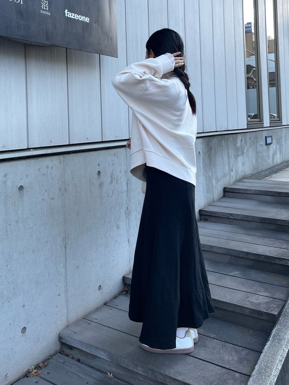 ホワイト系のボストンバッグ、ベージュ系のスニーカー、ブラック系のスカートを着用したレディースの春コーディネートの2枚目の写真