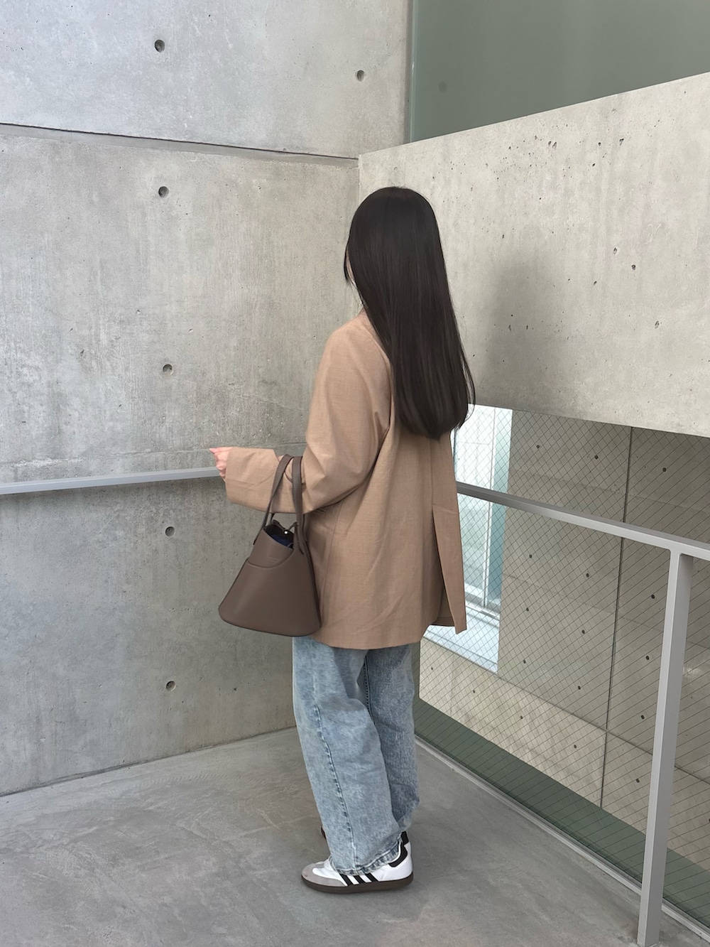 ベージュ系のジャケット/アウター、グレー系のバッグ、ブルー系のデニムパンツを着用したレディースの冬コーディネートの3枚目の写真