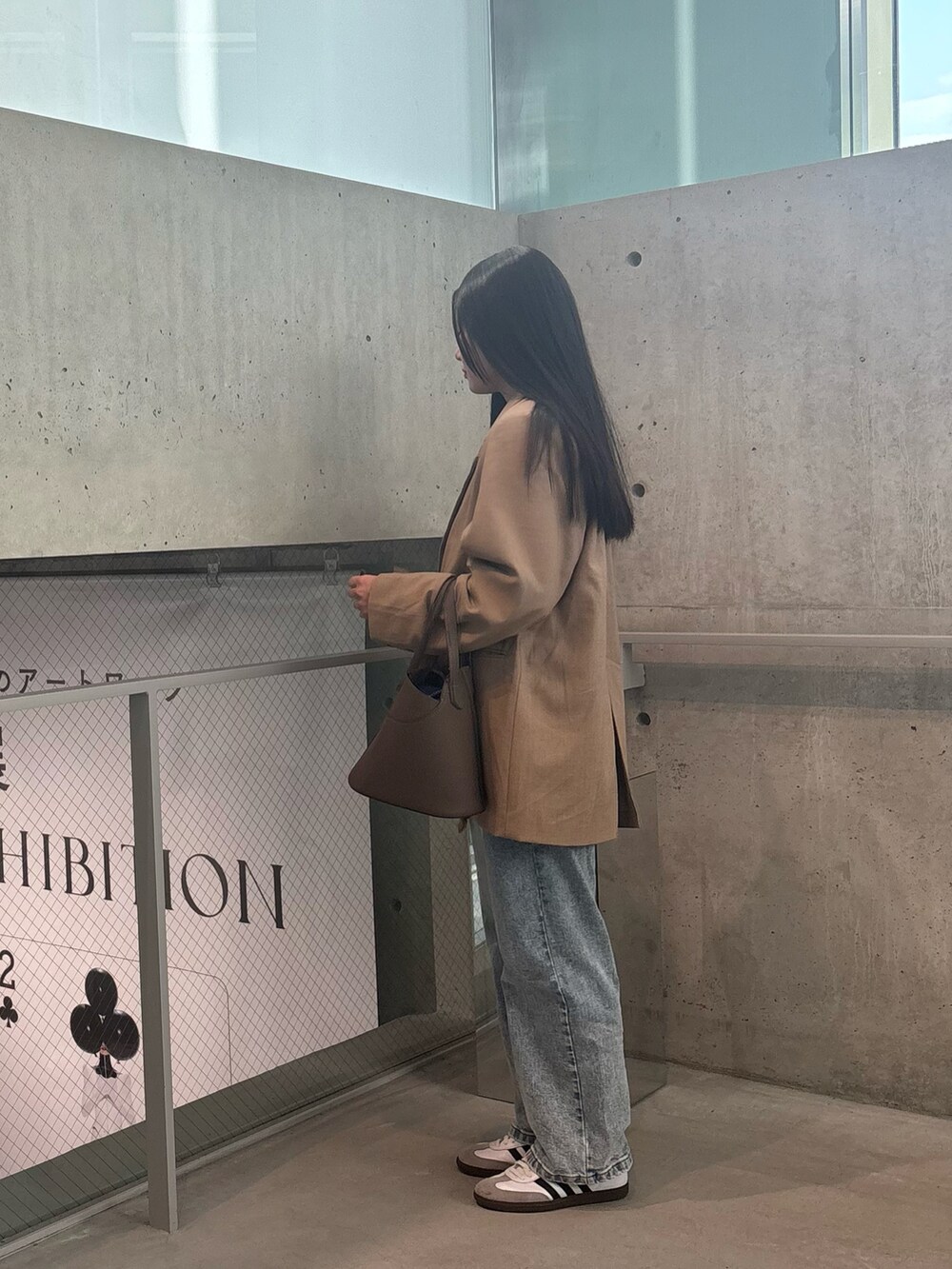 ベージュ系のジャケット/アウター、グレー系のバッグ、ブルー系のデニムパンツを着用したレディースの冬コーディネートの2枚目の写真