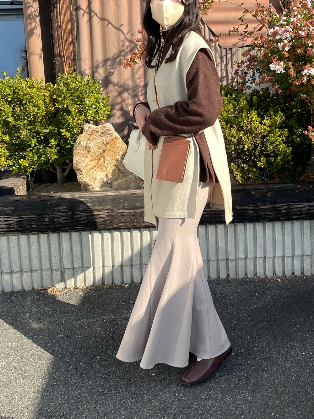 ホワイト系のボストンバッグ、ベージュ系のスカート、ブラウン系のニット/セーターを着用したレディースの冬コーディネートの2枚目の写真