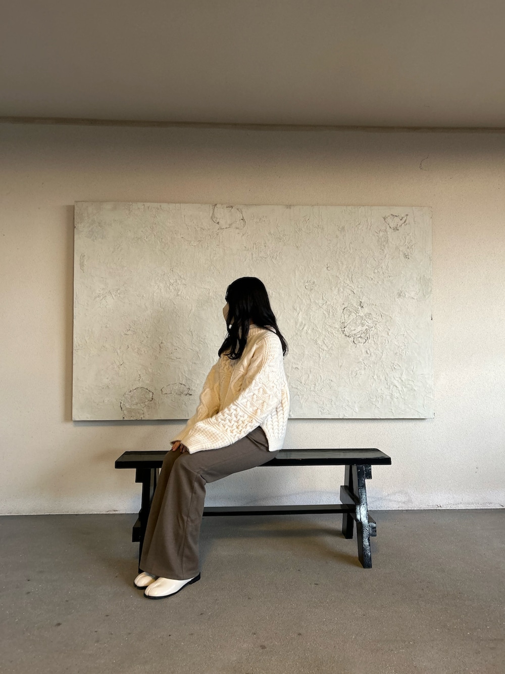 ブラウン系のパンツ、ホワイト系のブーツ、ベージュ系のハンドバッグを着用したレディースの冬コーディネートの3枚目の写真