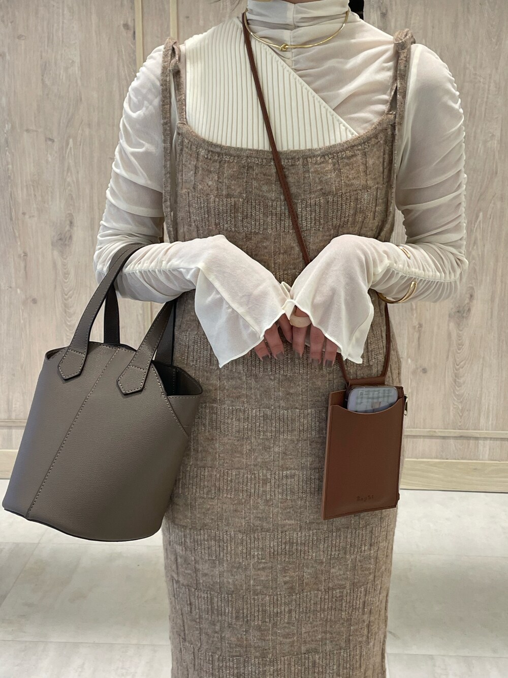 グレー系のバッグ、ホワイト系のその他トップス、ブラウン系のワンピースを着用したレディースの秋コーディネートの2枚目の写真