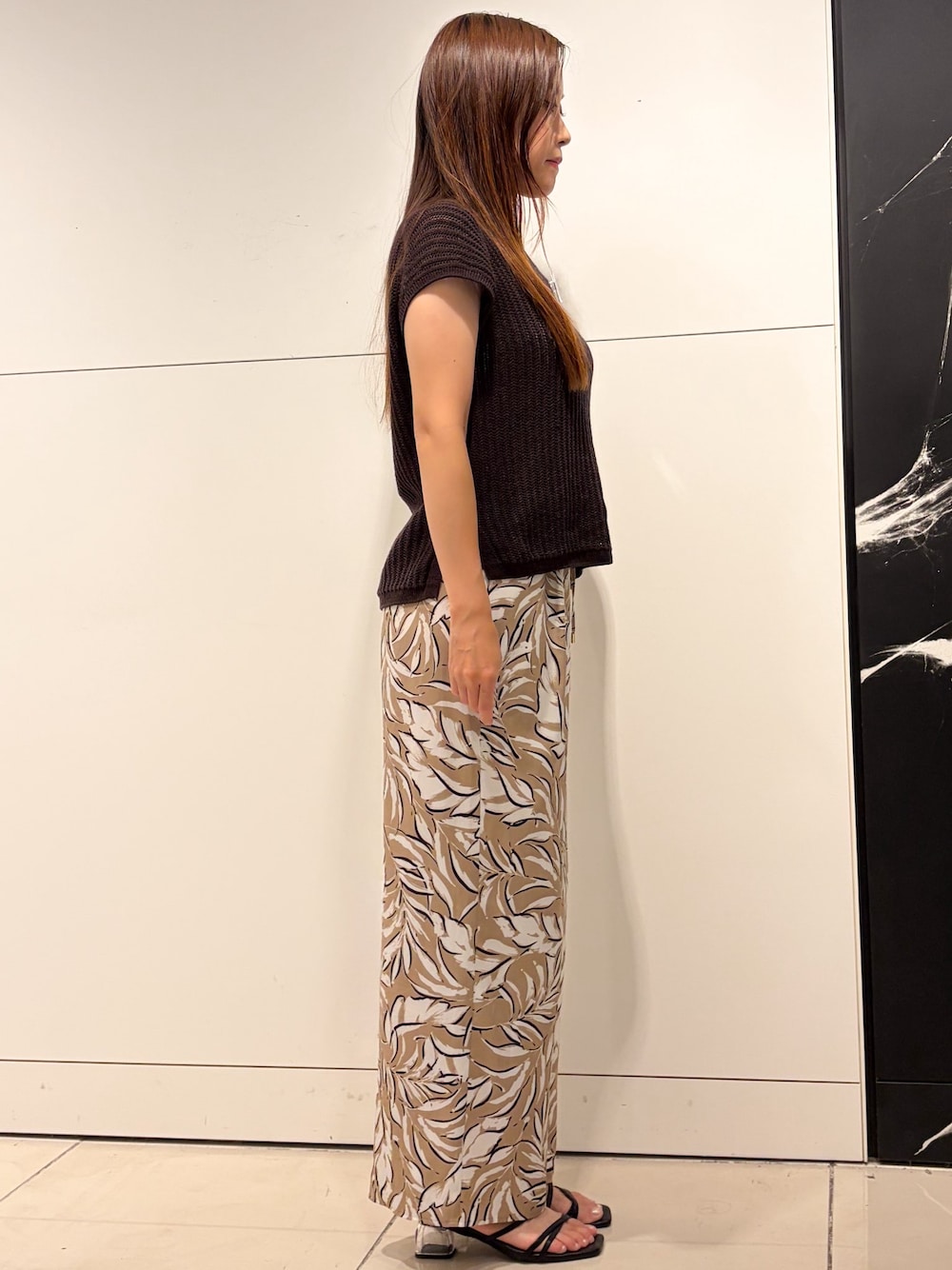 ブラウン系のニット/セーター、ベージュ系のその他パンツ、ブラック系のショルダーバッグを着用したレディースの夏コーディネートの2枚目の写真