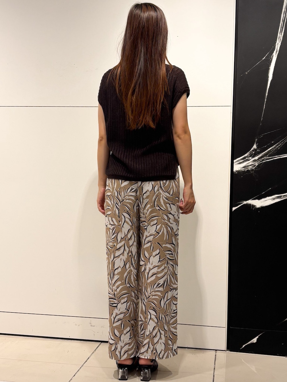 ブラウン系のニット/セーター、ベージュ系のその他パンツ、ブラック系のショルダーバッグを着用したレディースの夏コーディネートの3枚目の写真