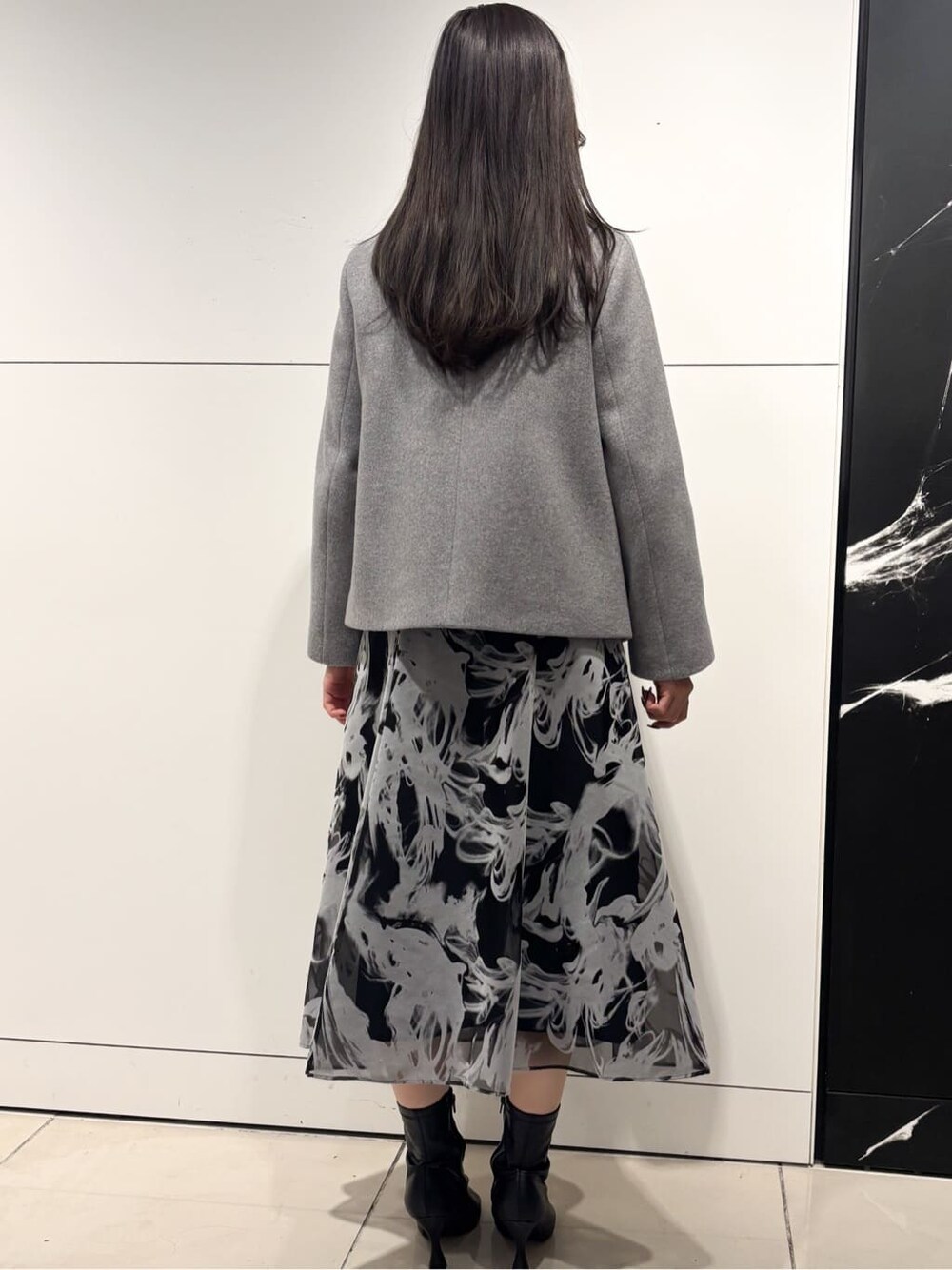 グレー系のスカート、グレー系のその他アウター、シルバー系のネックレスを着用したレディースの冬コーディネートの3枚目の写真