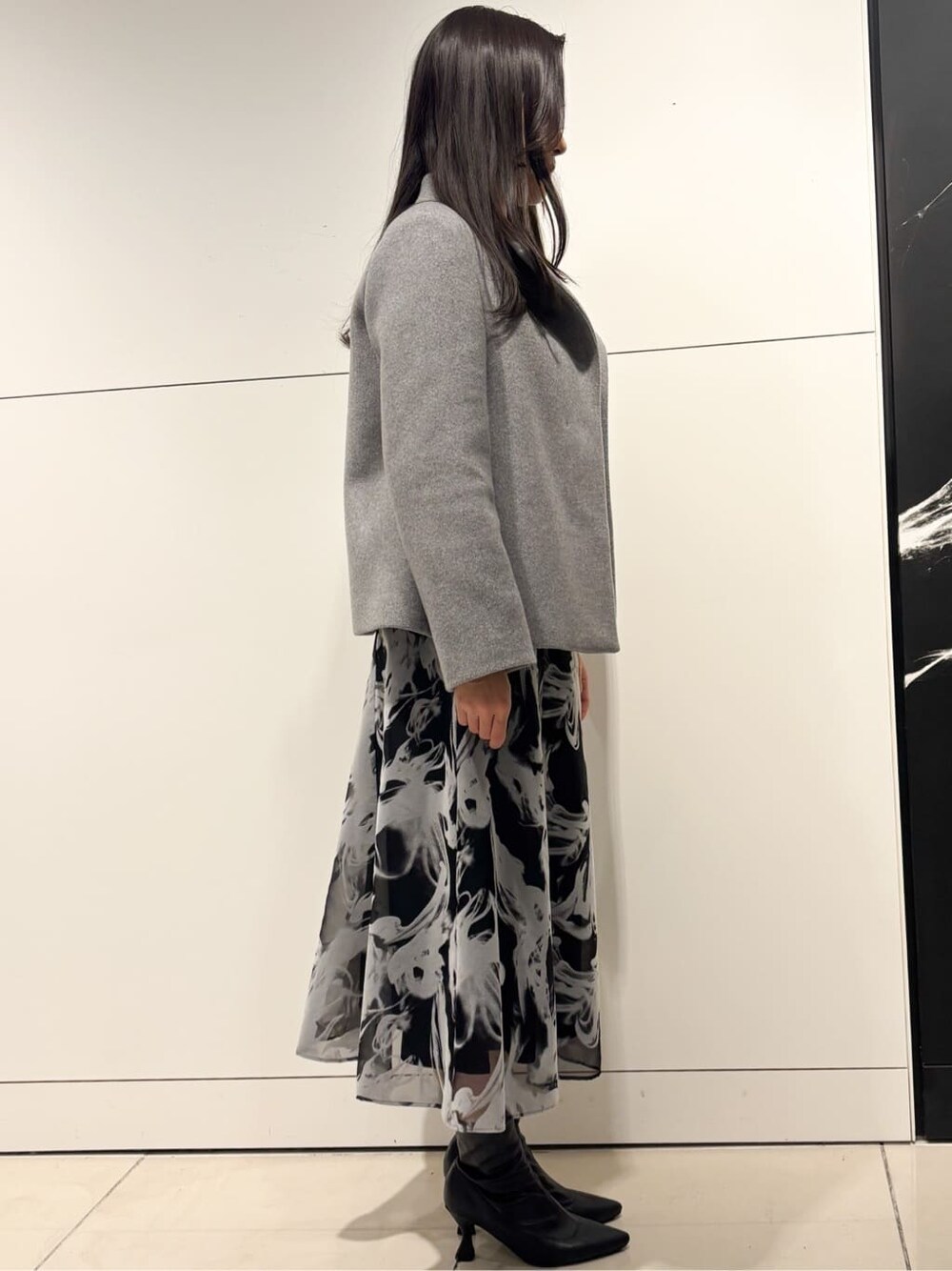 グレー系のスカート、グレー系のその他アウター、シルバー系のネックレスを着用したレディースの冬コーディネートの2枚目の写真
