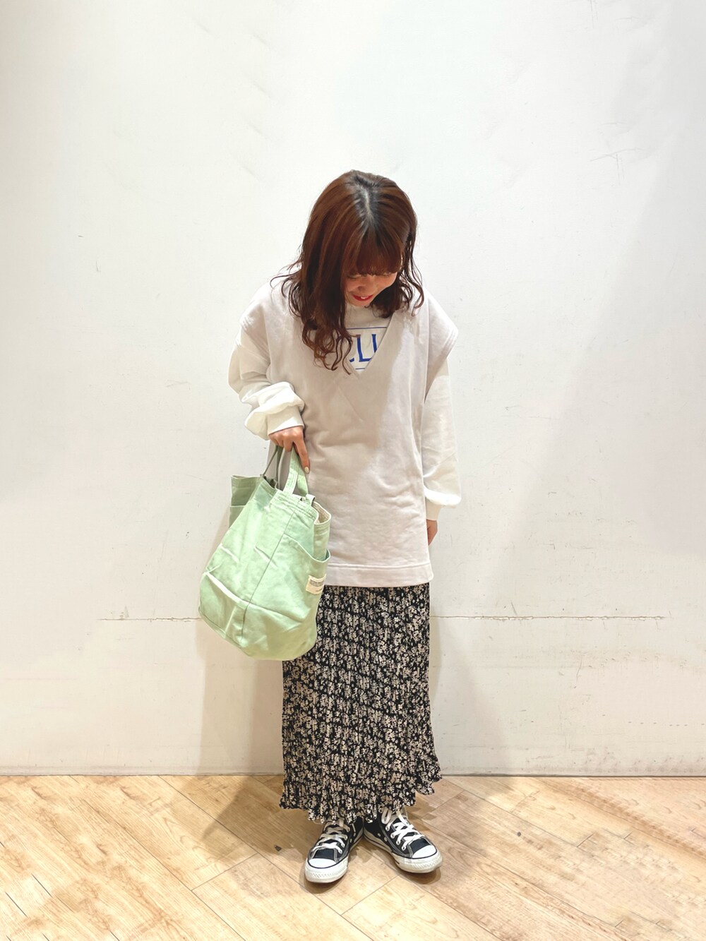 ホワイト系のステンカラーコート、ブラック系のスカート、ホワイト系のTシャツ/カットソーを着用したレディースの冬コーディネートの2枚目の写真