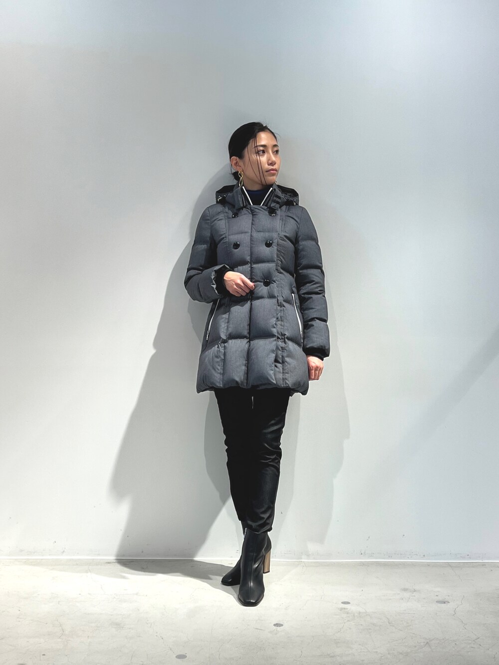 ブラック系のダウンジャケット/コート、グレー系のニット/セーター、ブラック系のブーツを着用したレディースの冬コーディネートの2枚目の写真