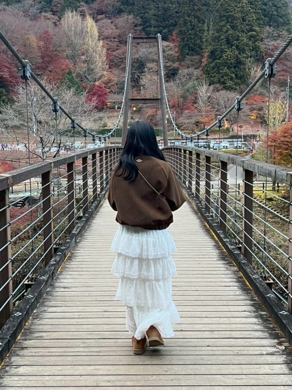 ホワイト系のスカート、ブラウン系のブーティ、ブラウン系のブルゾンを着用したレディースの秋コーディネートの2枚目の写真