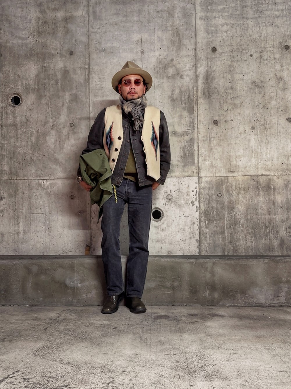 ベージュ系のベスト、グリーン系のニット/セーター、グリーン系のミリタリージャケットを着用したメンズの冬コーディネートの3枚目の写真