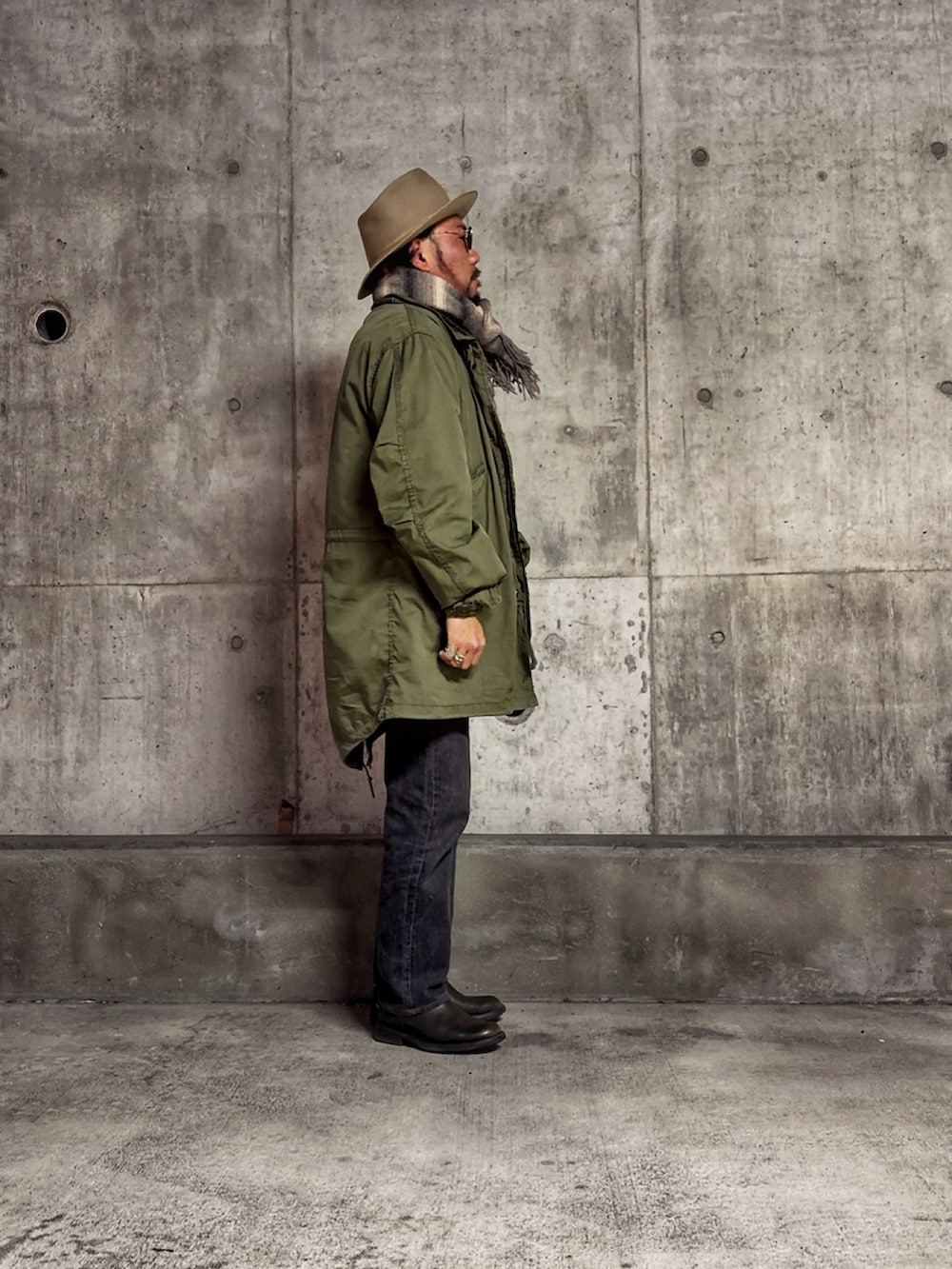 ベージュ系のベスト、グリーン系のニット/セーター、グリーン系のミリタリージャケットを着用したメンズの冬コーディネートの2枚目の写真