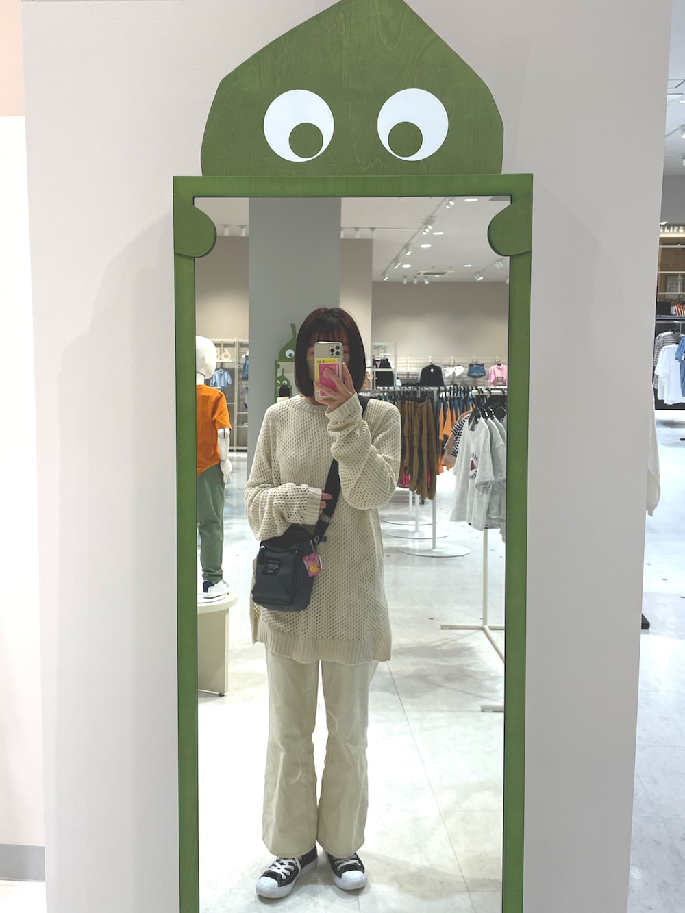 ブラック系のスニーカー、ホワイト系のデニムパンツ、グレー系のショルダーバッグを着用したレディースの春コーディネートの2枚目の写真