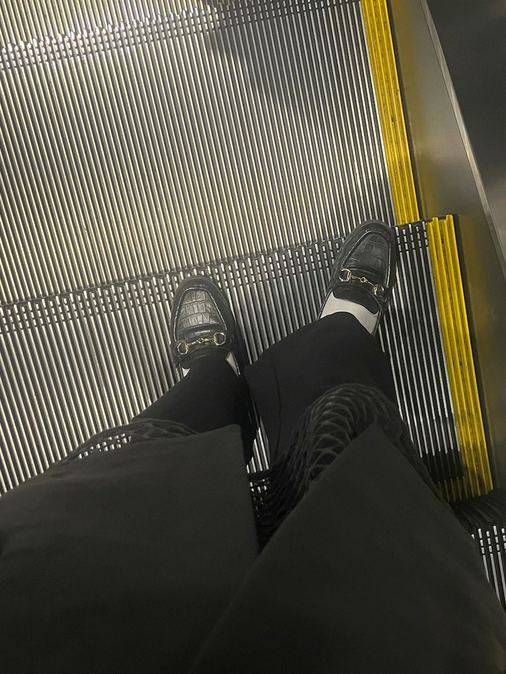 グリーン系のトートバッグ、ブラック系のTシャツ/カットソー、ブラック系のスラックスを着用したレディースの秋コーディネートの2枚目の写真