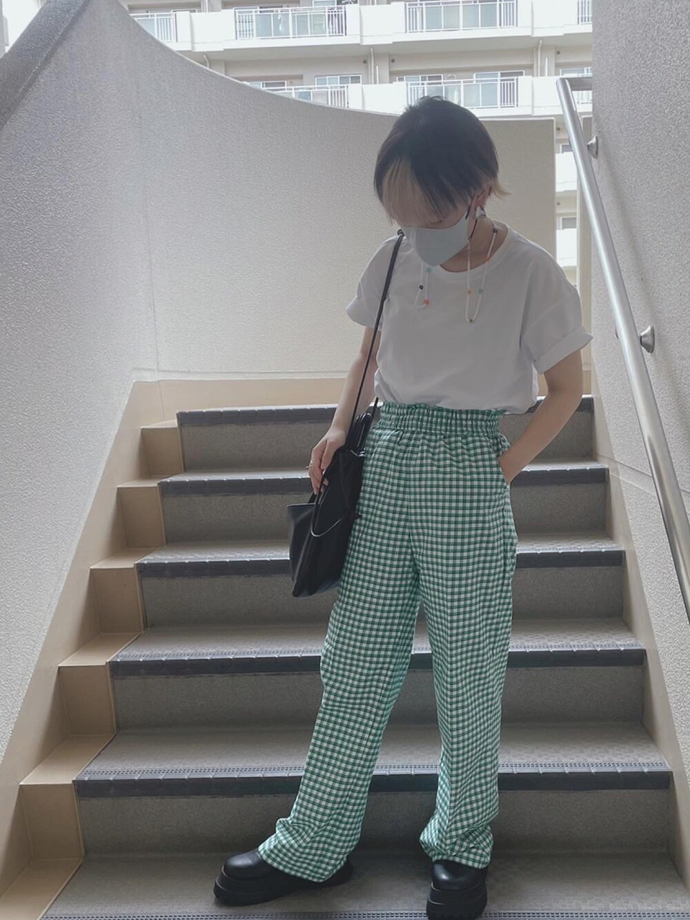 グリーン系のパンツ、ブラック系のショルダーバッグ、ホワイト系のTシャツ/カットソーを着用したレディースの夏コーディネートの2枚目の写真