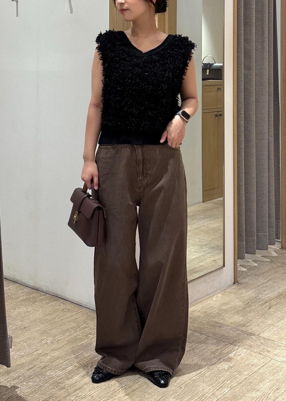 ブラウン系のショルダーバッグ、ブラック系のパンプス、ブラック系のベストを着用したレディースの秋コーディネートの9枚目の写真