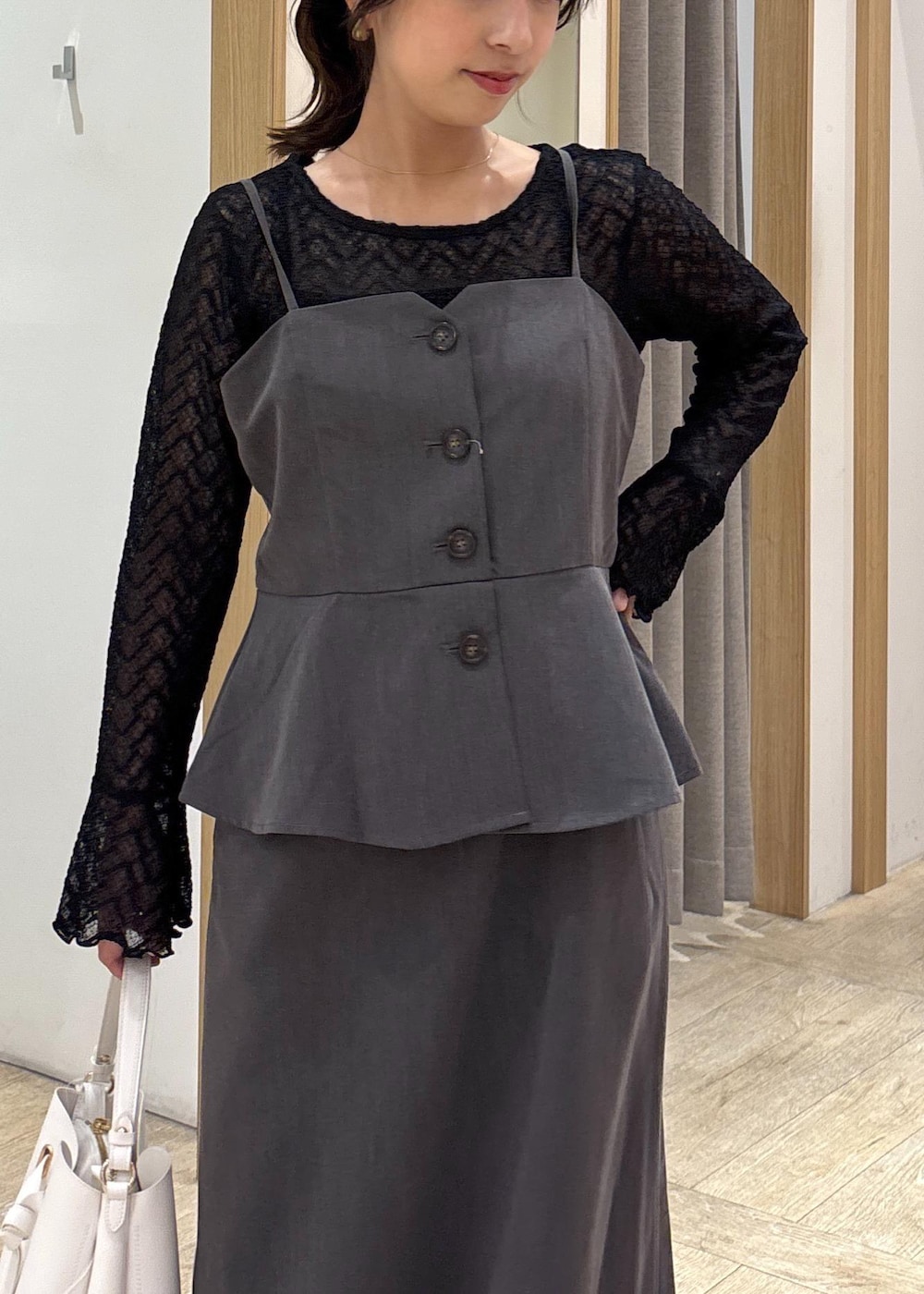 ホワイト系のショルダーバッグ、ブラック系のパンプス、グレー系のワンピースを着用したレディースの秋コーディネートの4枚目の写真