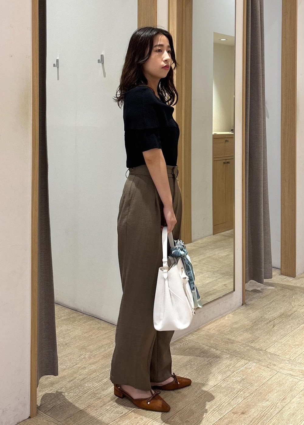 ホワイト系のショルダーバッグ、グリーン系のスラックス、ブラック系のニット/セーターを着用したレディースの夏コーディネートの2枚目の写真