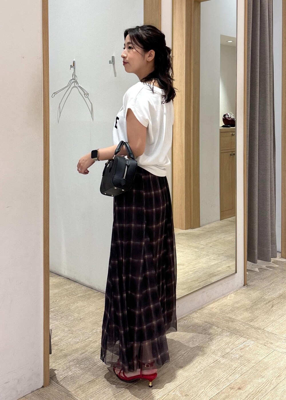 レッド系のサンダル、ブラック系のショルダーバッグ、ブラウン系のスカートを着用したレディースの夏コーディネートの2枚目の写真