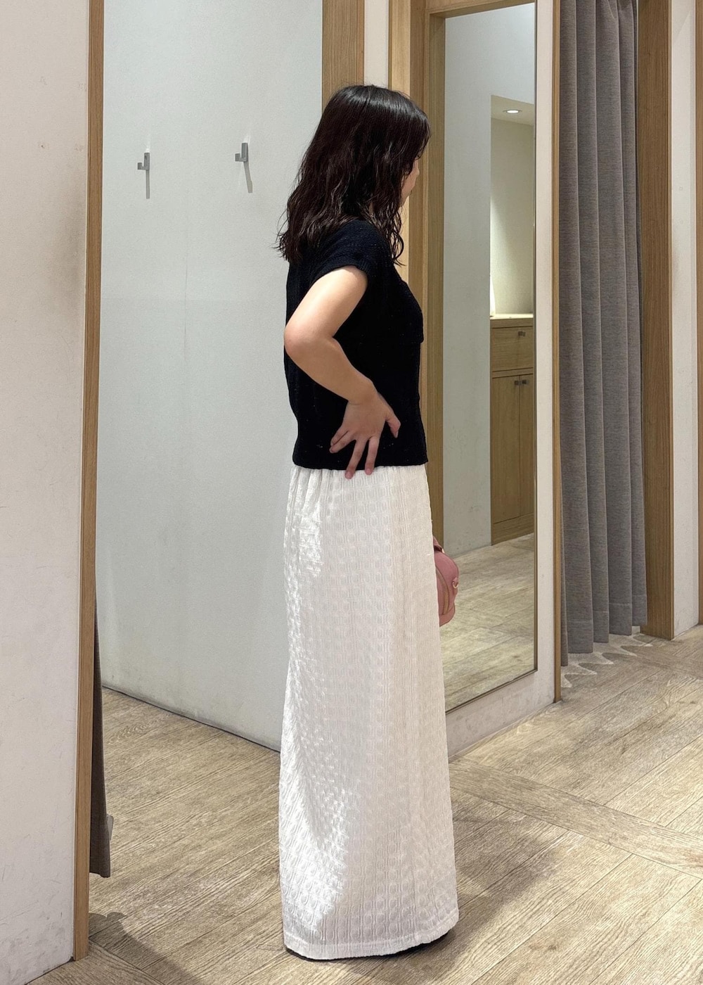 ホワイト系のスカート、ブラック系のカーディガン/ボレロ、ブラック系のパンプスを着用したレディースの夏コーディネートの4枚目の写真