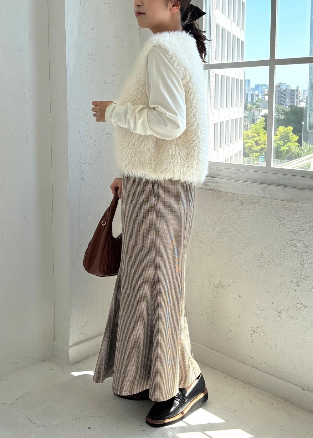 ブラック系のローファー、ベージュ系のスカート、ホワイト系のTシャツ/カットソーを着用したレディースの夏コーディネートの2枚目の写真