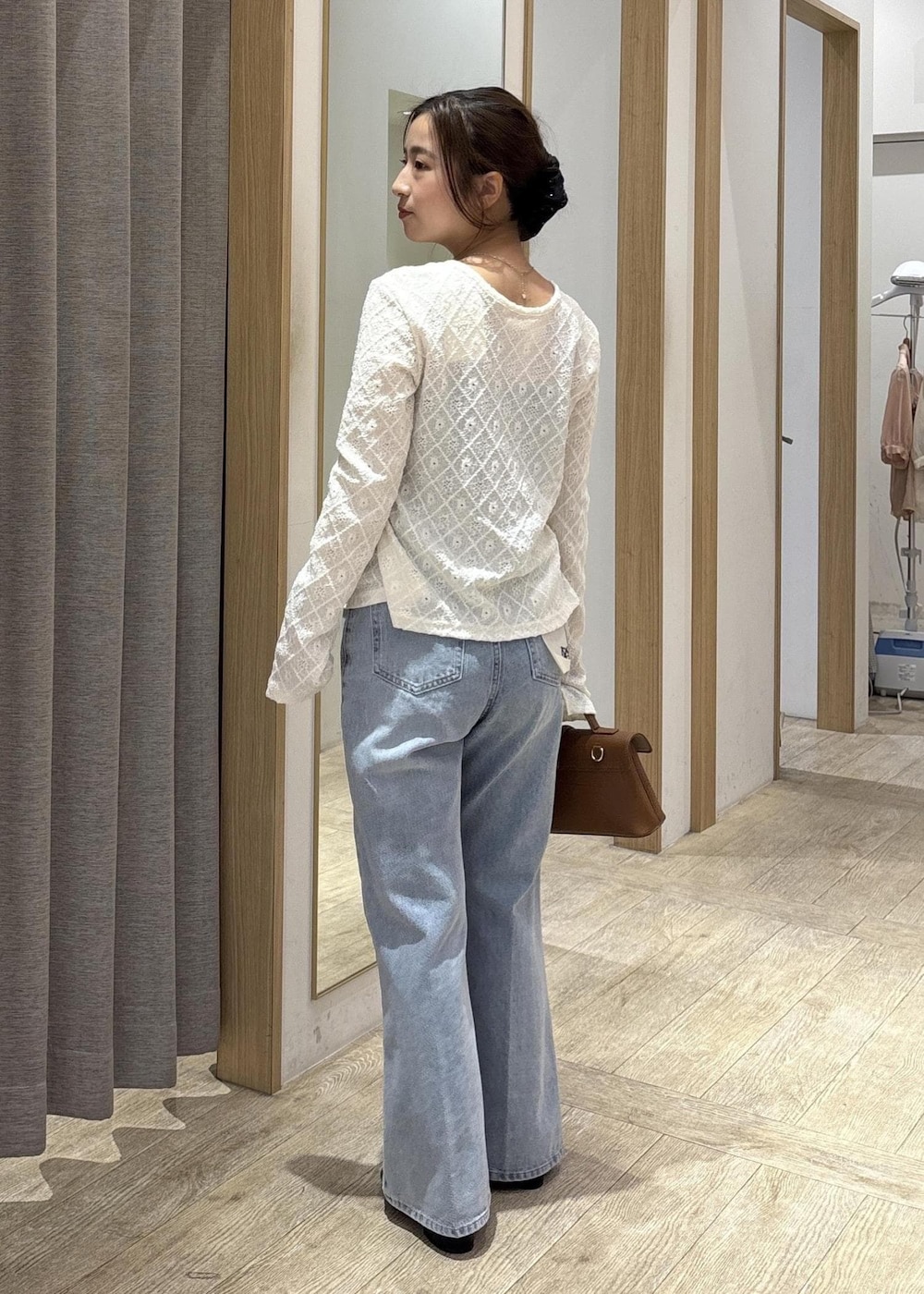 イエロー系のショルダーバッグ、ホワイト系のカーディガン/ボレロ、ブルー系のデニムパンツを着用したレディースの春コーディネートの2枚目の写真