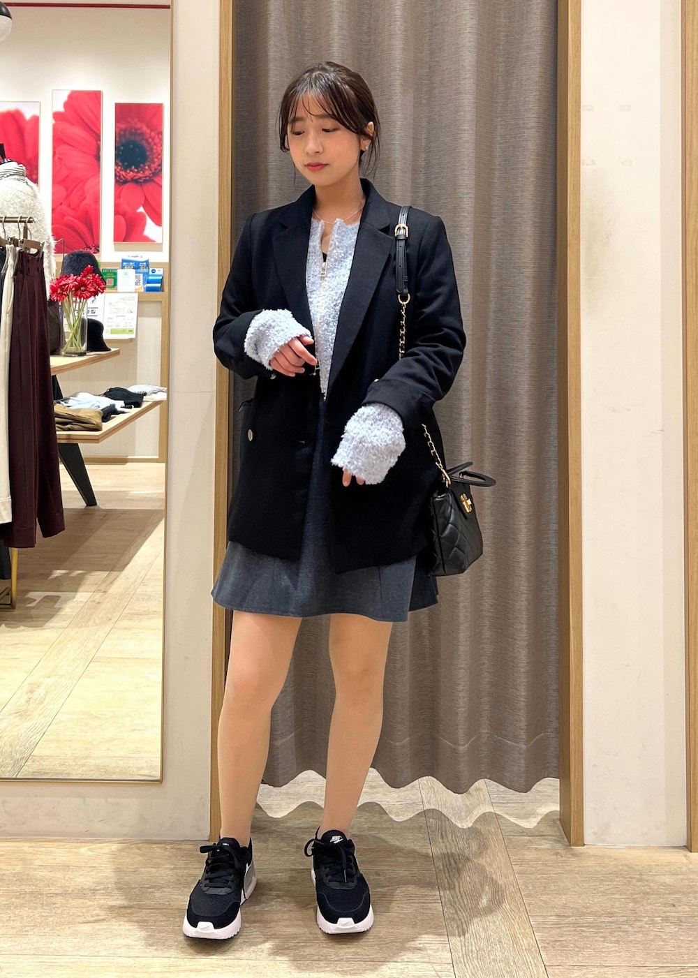 ブラック系のテーラードジャケット、ブラック系のスニーカー、ブルー系のカーディガン/ボレロを着用したレディースの冬コーディネートの2枚目の写真