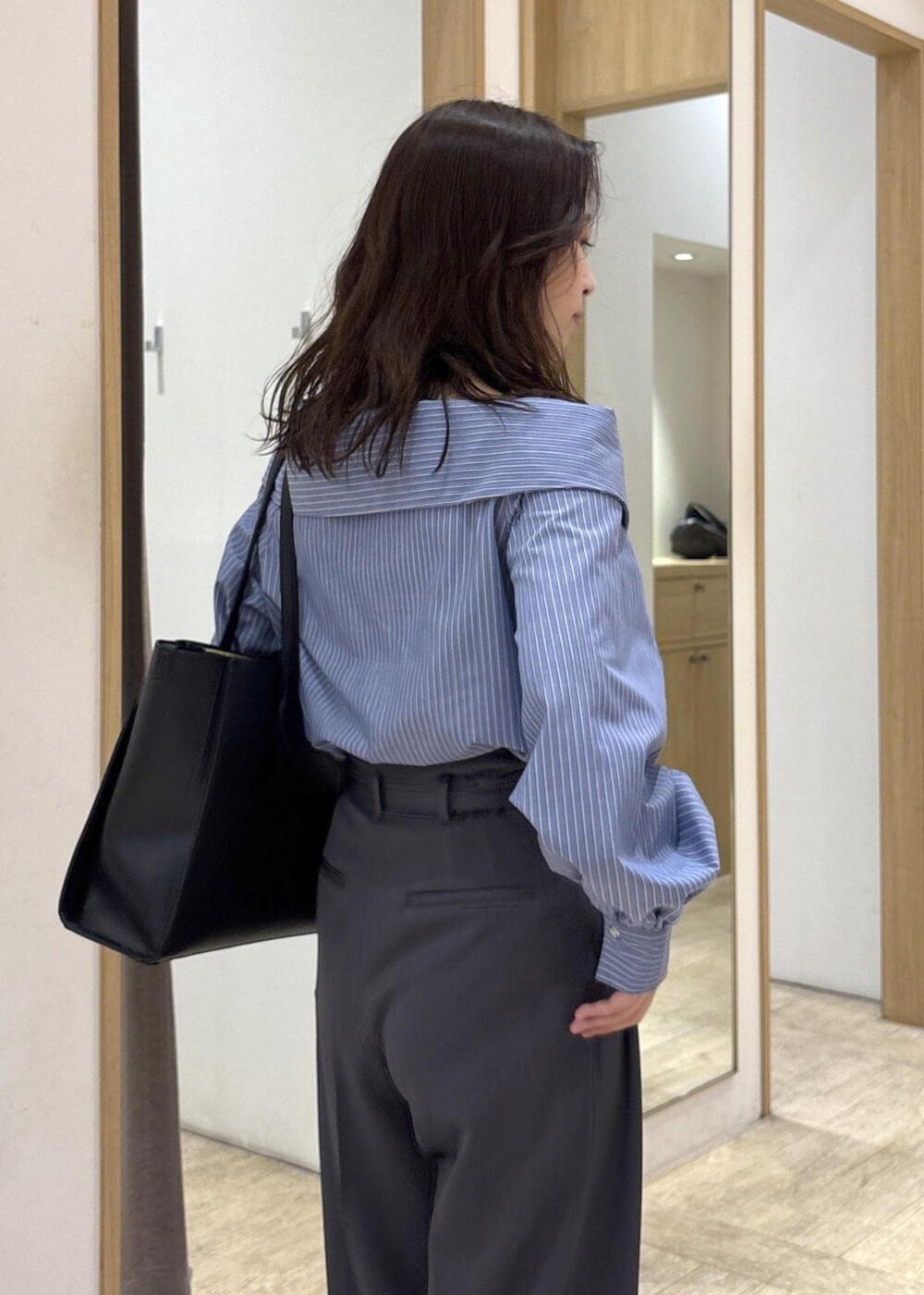 ブラック系のトートバッグ、ブラック系のパンプス、ブルー系のシャツ/ブラウスを着用したレディースの秋コーディネートの7枚目の写真