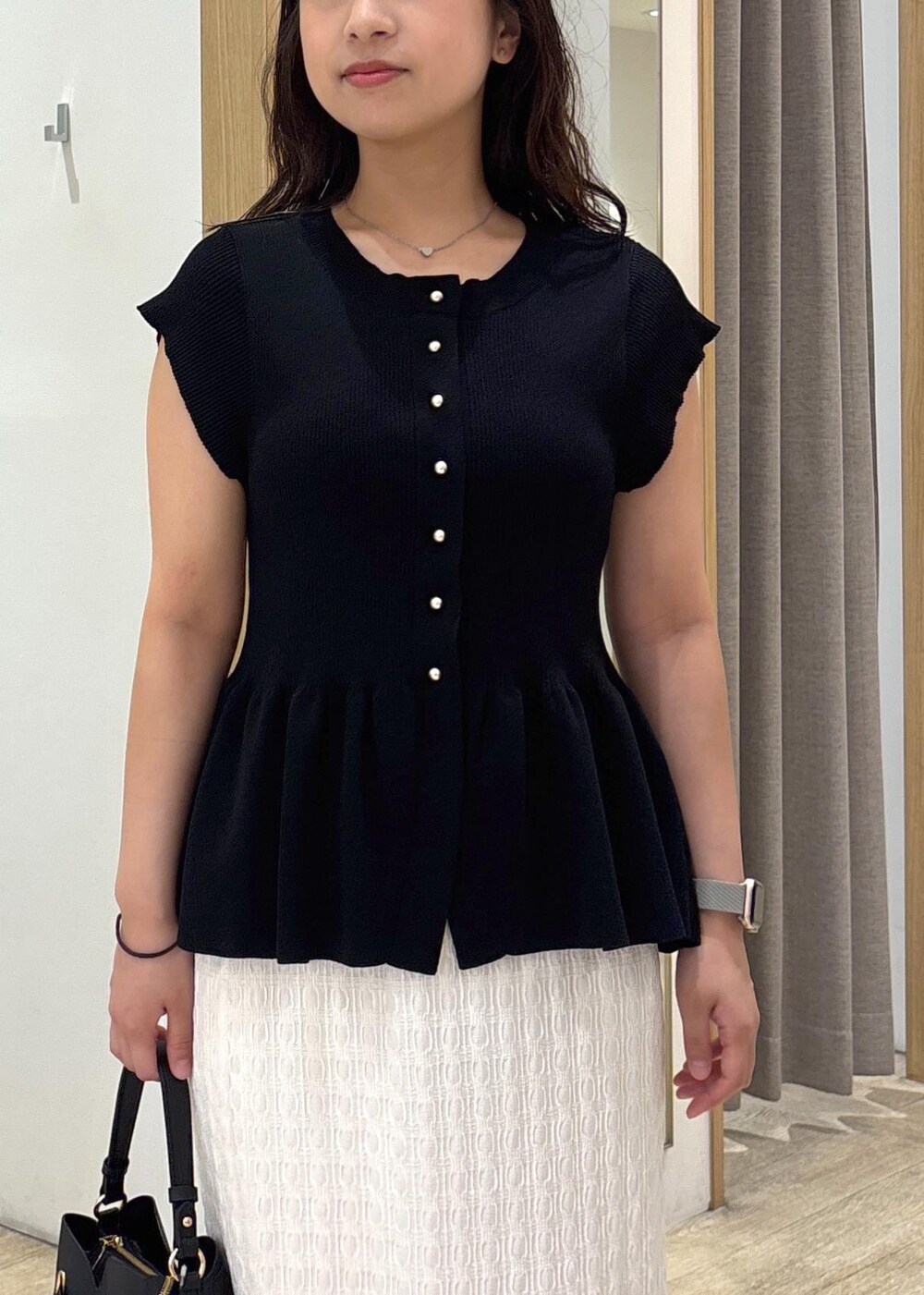 ブラック系のパンプス、ホワイト系のスカート、ブラック系のショルダーバッグを着用したレディースの夏コーディネートの5枚目の写真