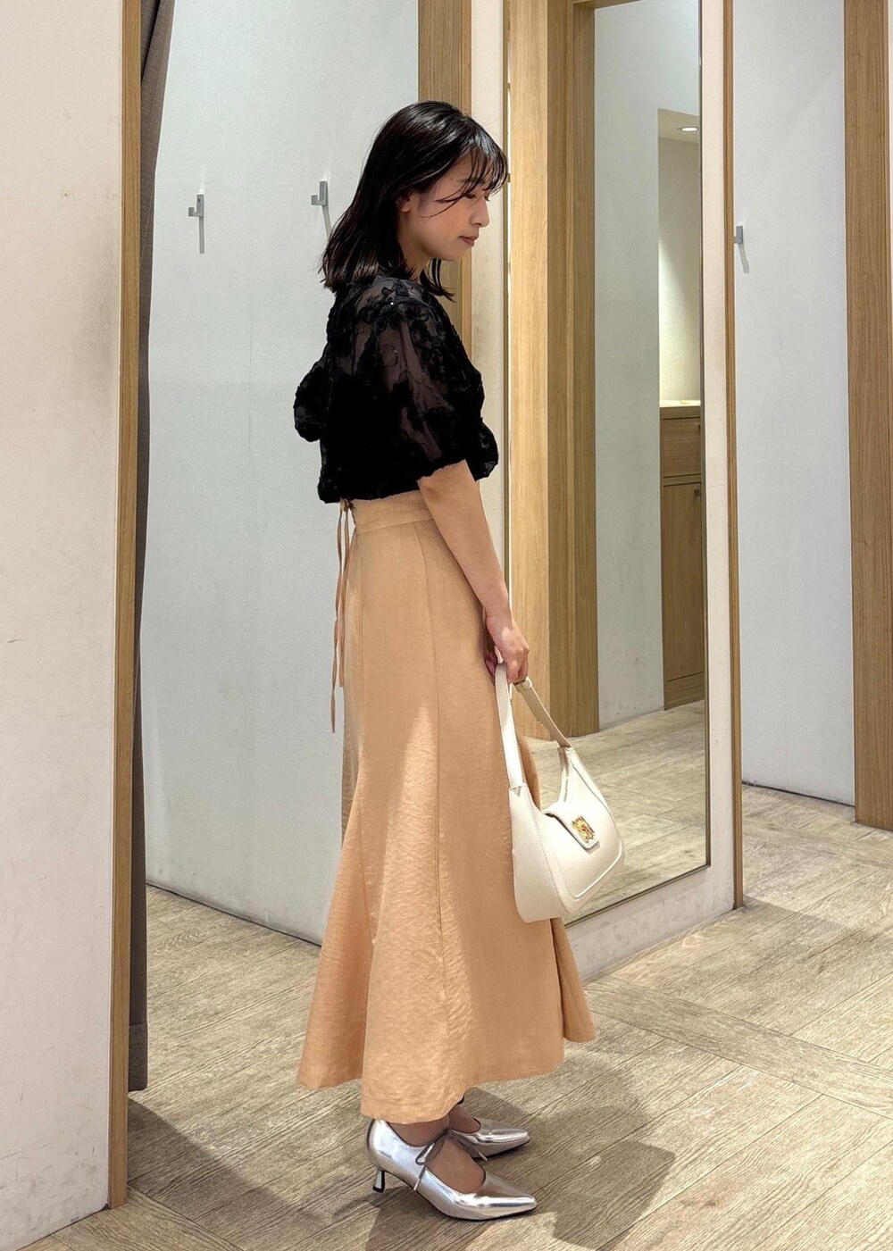 ホワイト系のハンドバッグ、シルバー系のパンプス、オレンジ系のスカートを着用したレディースの春コーディネートの3枚目の写真
