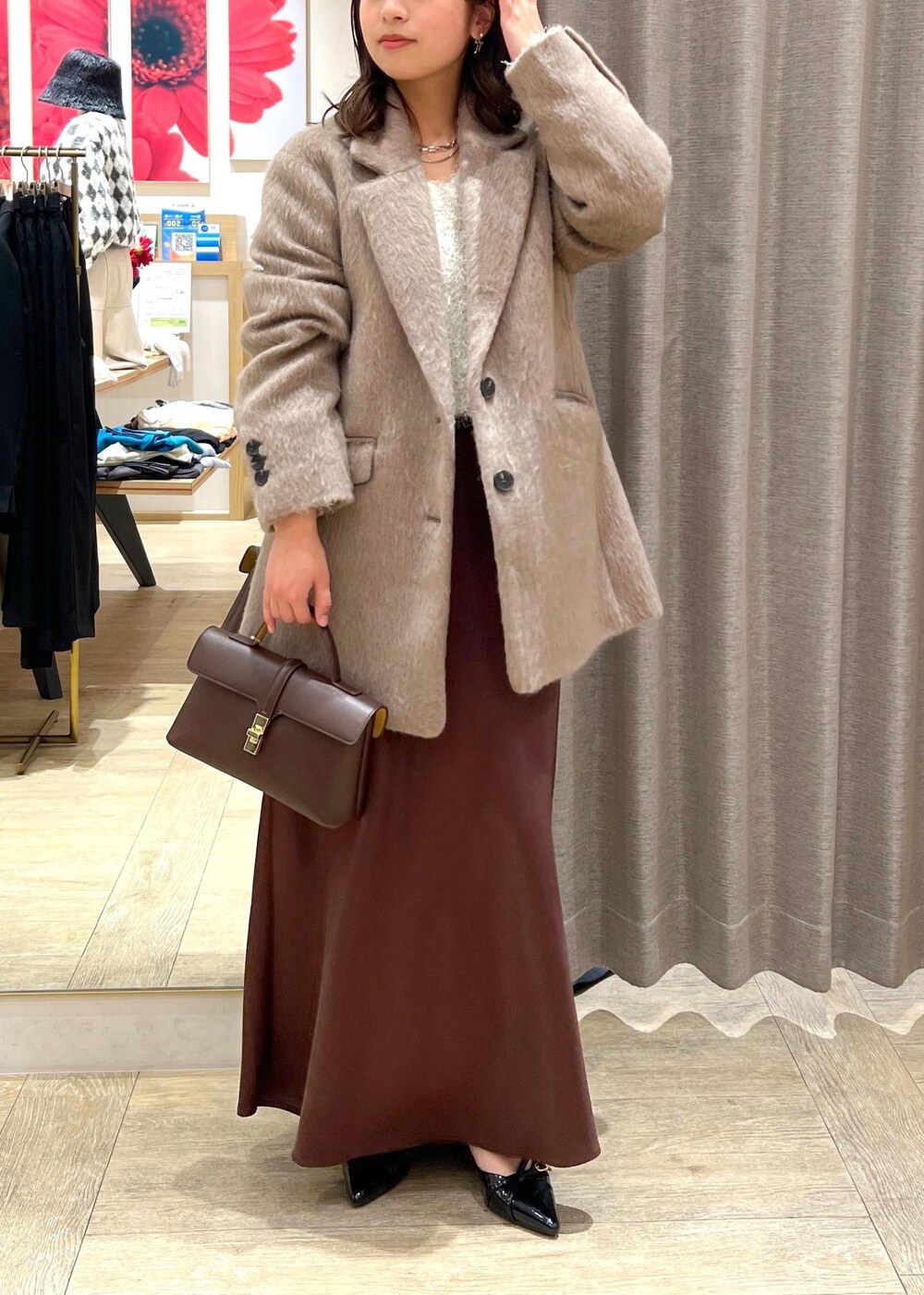 ブラック系のパンプス、ブラウン系のスカート、ホワイト系のニット/セーターを着用したレディースの冬コーディネートの6枚目の写真