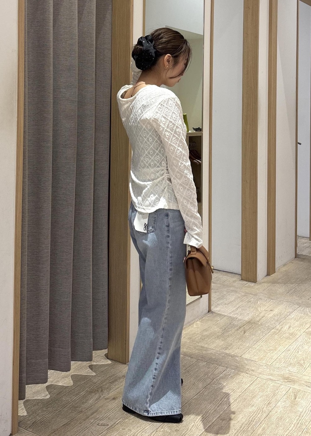 イエロー系のショルダーバッグ、ホワイト系のカーディガン/ボレロ、ブルー系のデニムパンツを着用したレディースの春コーディネートの3枚目の写真