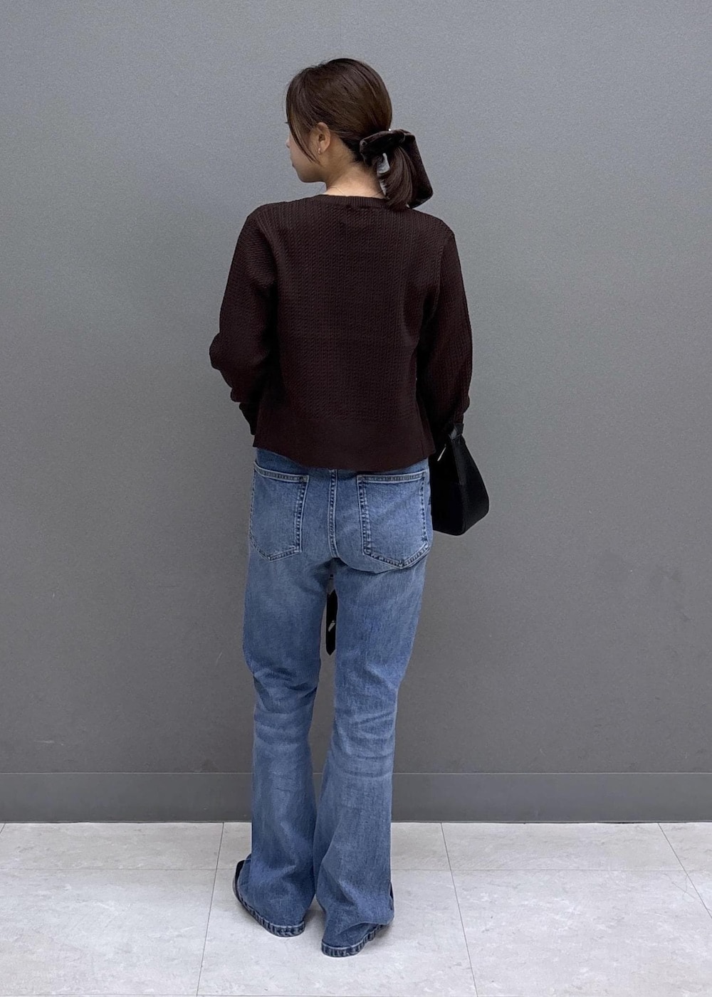 ブラック系のパンプス、ブルー系のデニムパンツ、ブラウン系のカーディガン/ボレロを着用したレディースの秋コーディネートの3枚目の写真