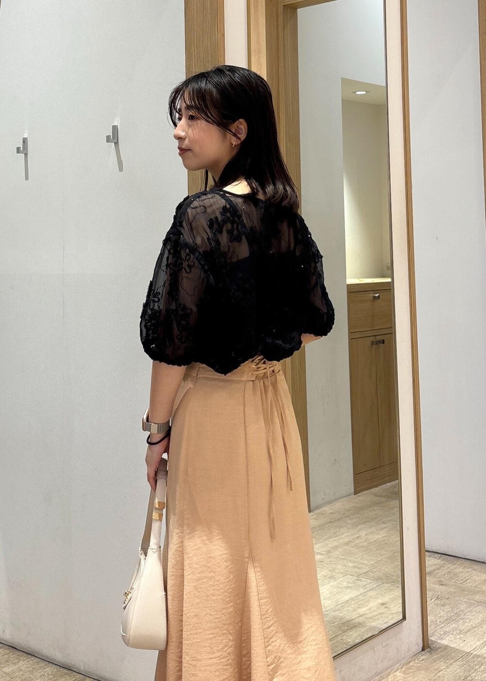 ホワイト系のハンドバッグ、シルバー系のパンプス、オレンジ系のスカートを着用したレディースの春コーディネートの7枚目の写真