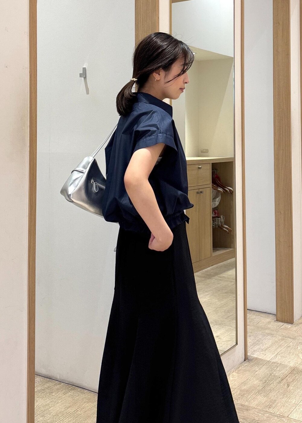 ホワイト系のキャミソール、シルバー系のパンプス、ブラック系のスカートを着用したレディースの春コーディネートの6枚目の写真