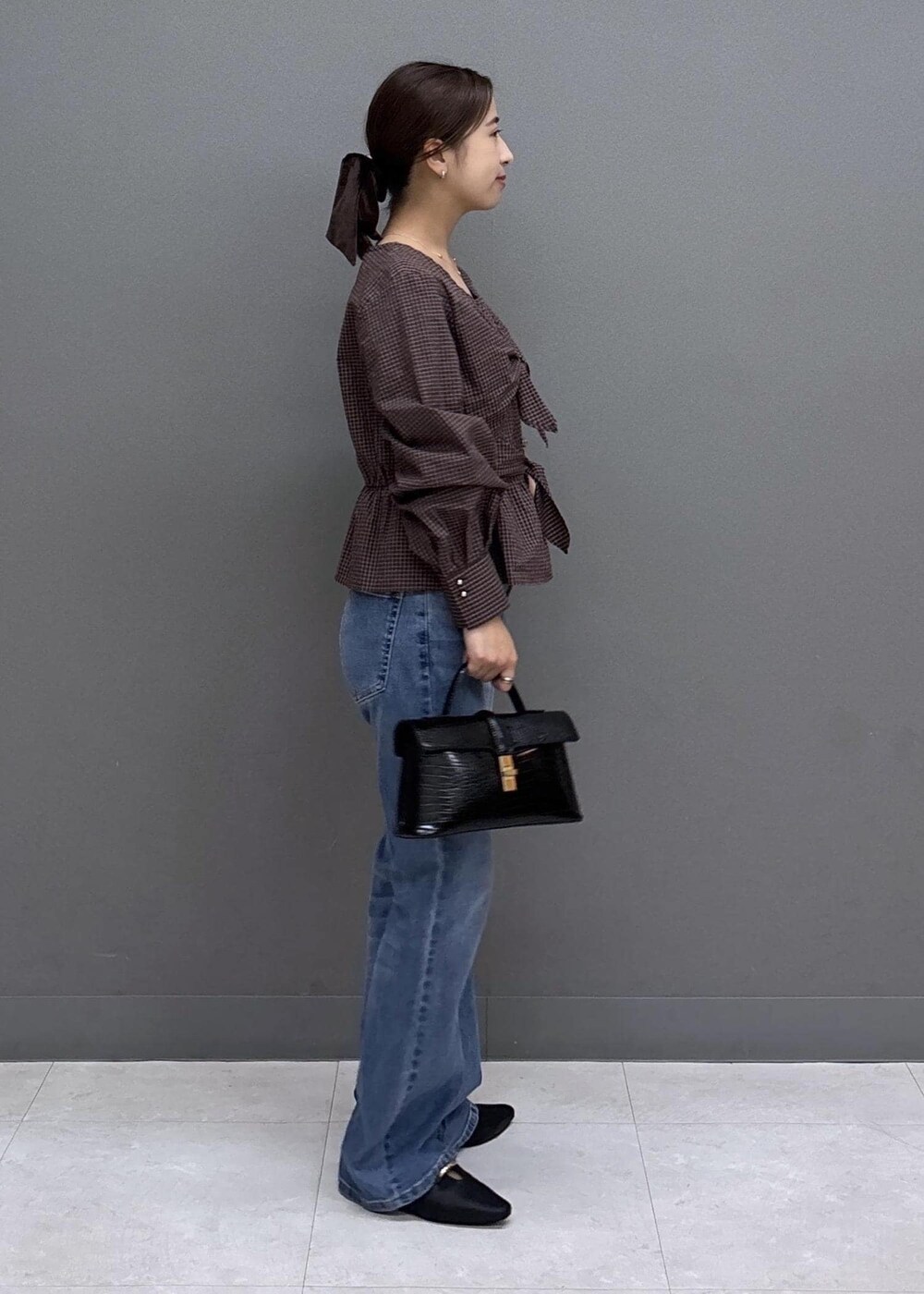 ブルー系のデニムパンツ、ブラック系のハンドバッグ、ブラック系のパンプスを着用したレディースの秋コーディネートの4枚目の写真
