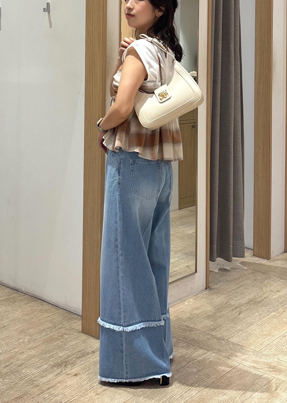 ブラック系のサンダル、ホワイト系のショルダーバッグ、ブルー系のデニムパンツを着用したレディースの夏コーディネートの2枚目の写真