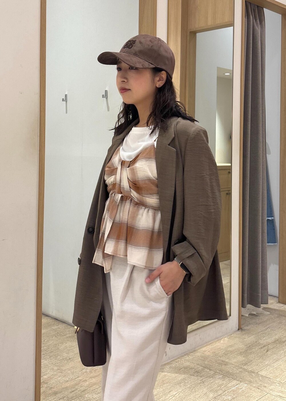 ブラウン系のショルダーバッグ、グリーン系のテーラードジャケット、ホワイト系のスラックスを着用したレディースの夏コーディネートの6枚目の写真