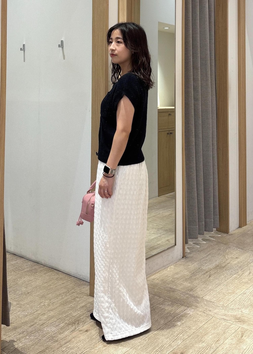 ホワイト系のスカート、ブラック系のカーディガン/ボレロ、ブラック系のパンプスを着用したレディースの夏コーディネートの2枚目の写真