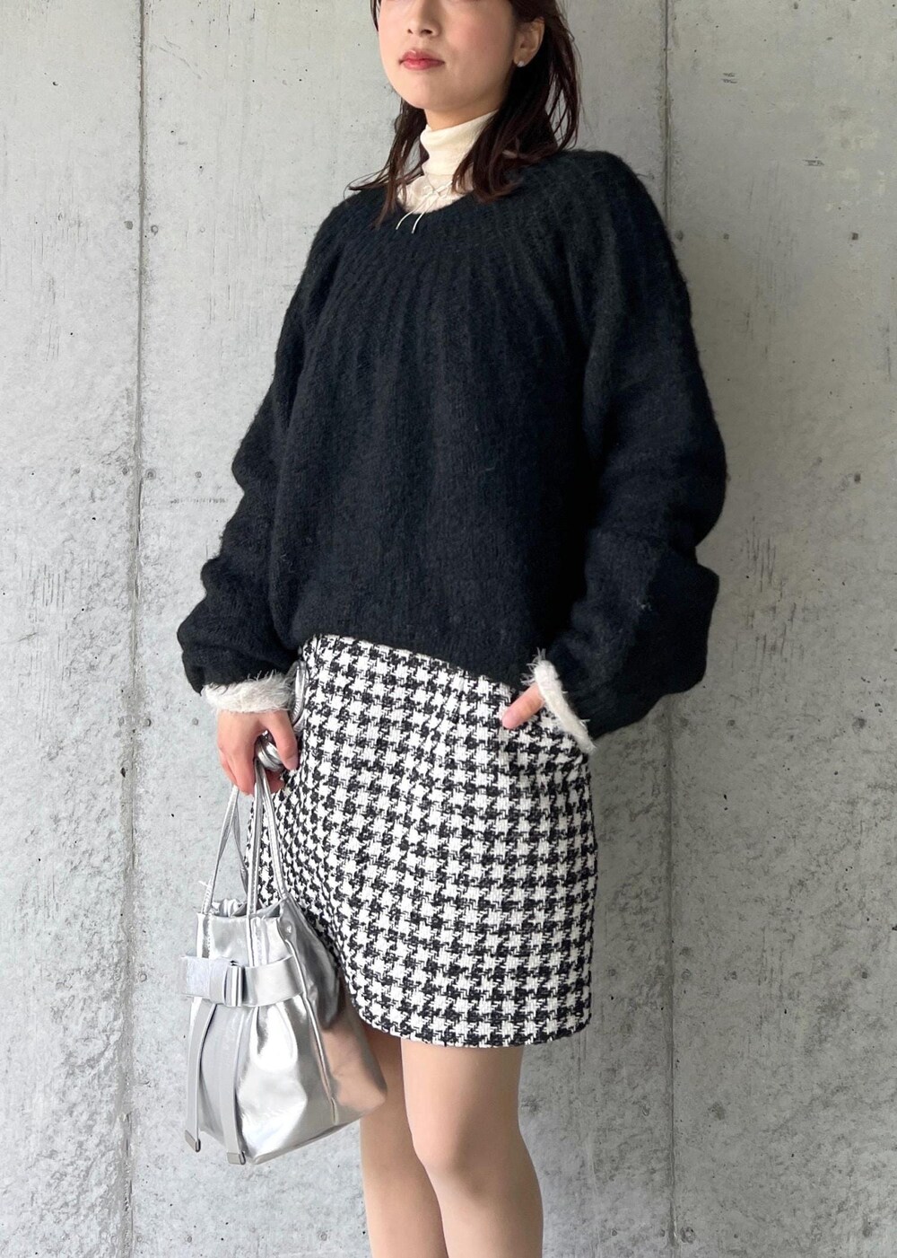 シルバー系のブーツ、ブラック系のスカート、ホワイト系のニット/セーターを着用したレディースの冬コーディネートの6枚目の写真