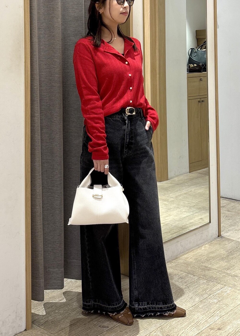 ブラウン系のパンプス、レッド系のカーディガン/ボレロ、ブラック系のデニムパンツを着用したレディースの春コーディネートの2枚目の写真