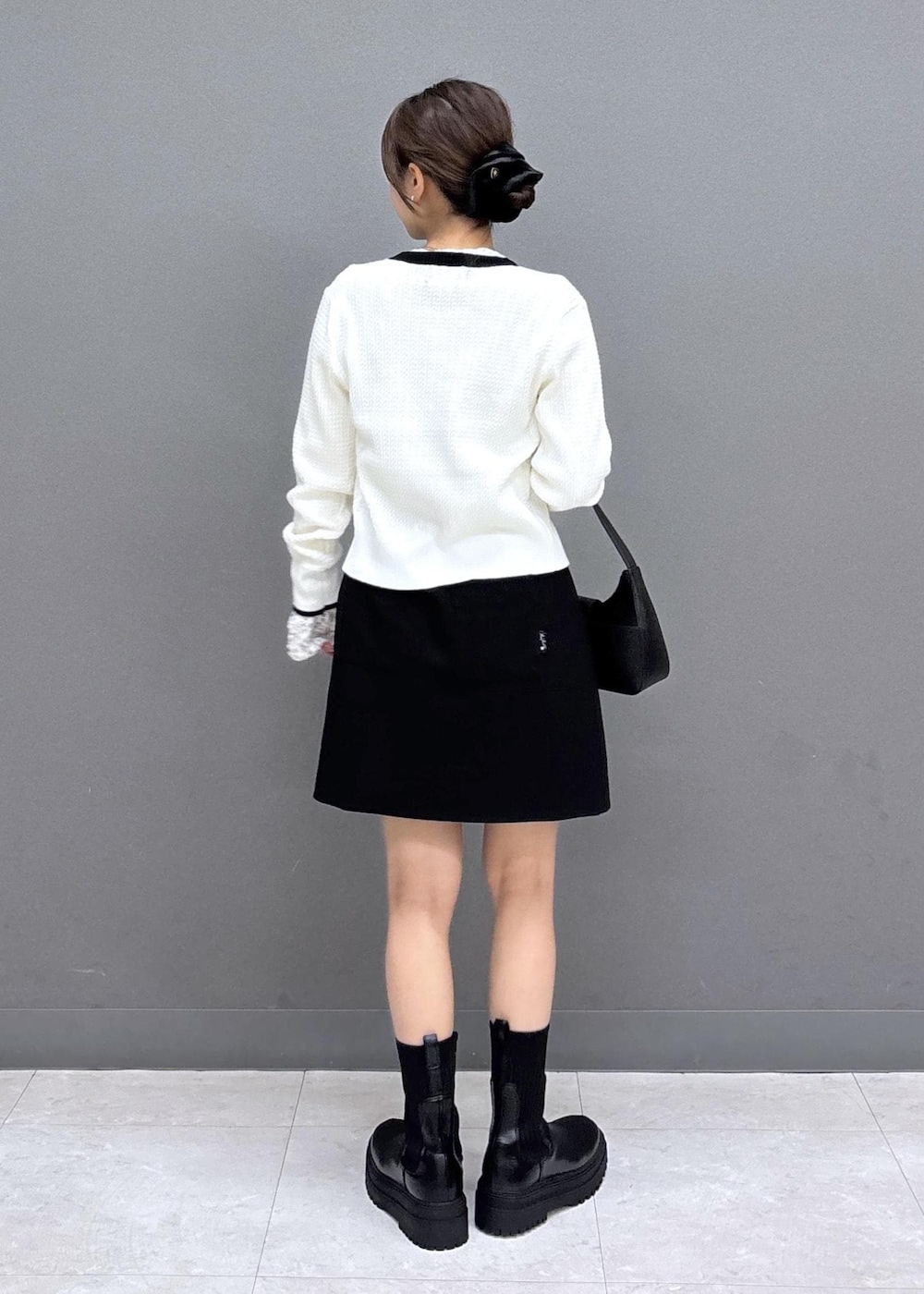 ブラック系のショルダーバッグ、ホワイト系のTシャツ/カットソー、ブラック系のブーツを着用したレディースの秋コーディネートの3枚目の写真