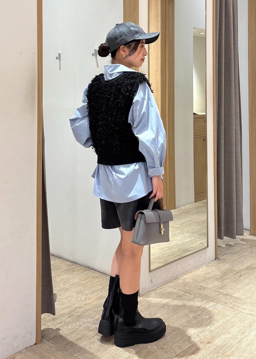 グレー系のショルダーバッグ、ブルー系のシャツ/ブラウス、ブラック系のベストを着用したレディースの秋コーディネートの4枚目の写真