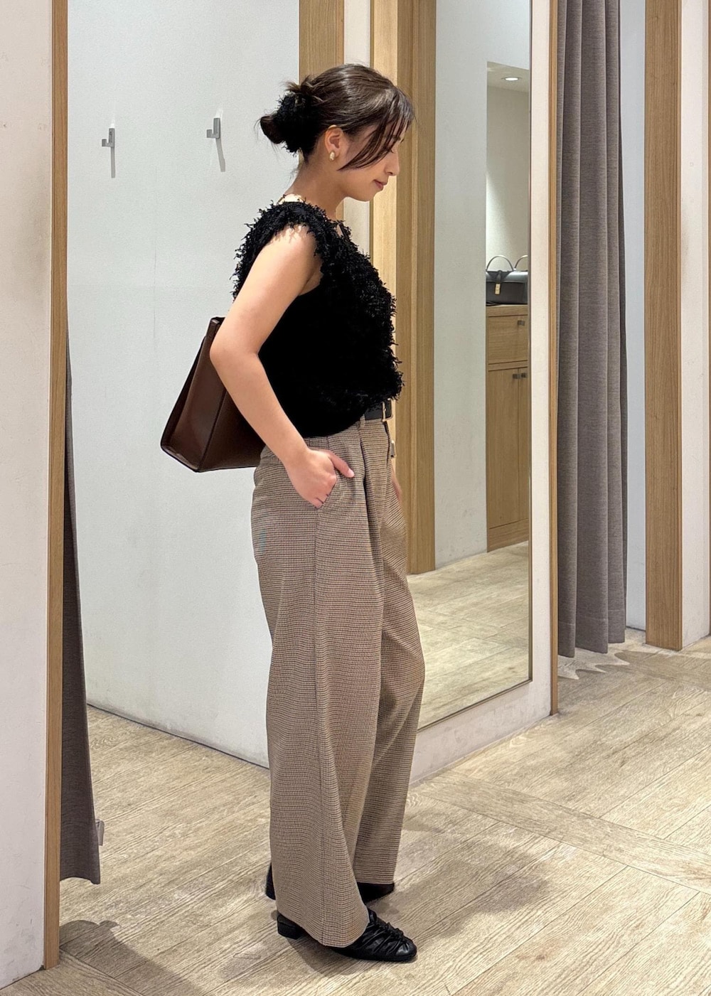 ブラック系のパンプス、ブラック系のベスト、ベージュ系のスラックスを着用したレディースの秋コーディネートの2枚目の写真