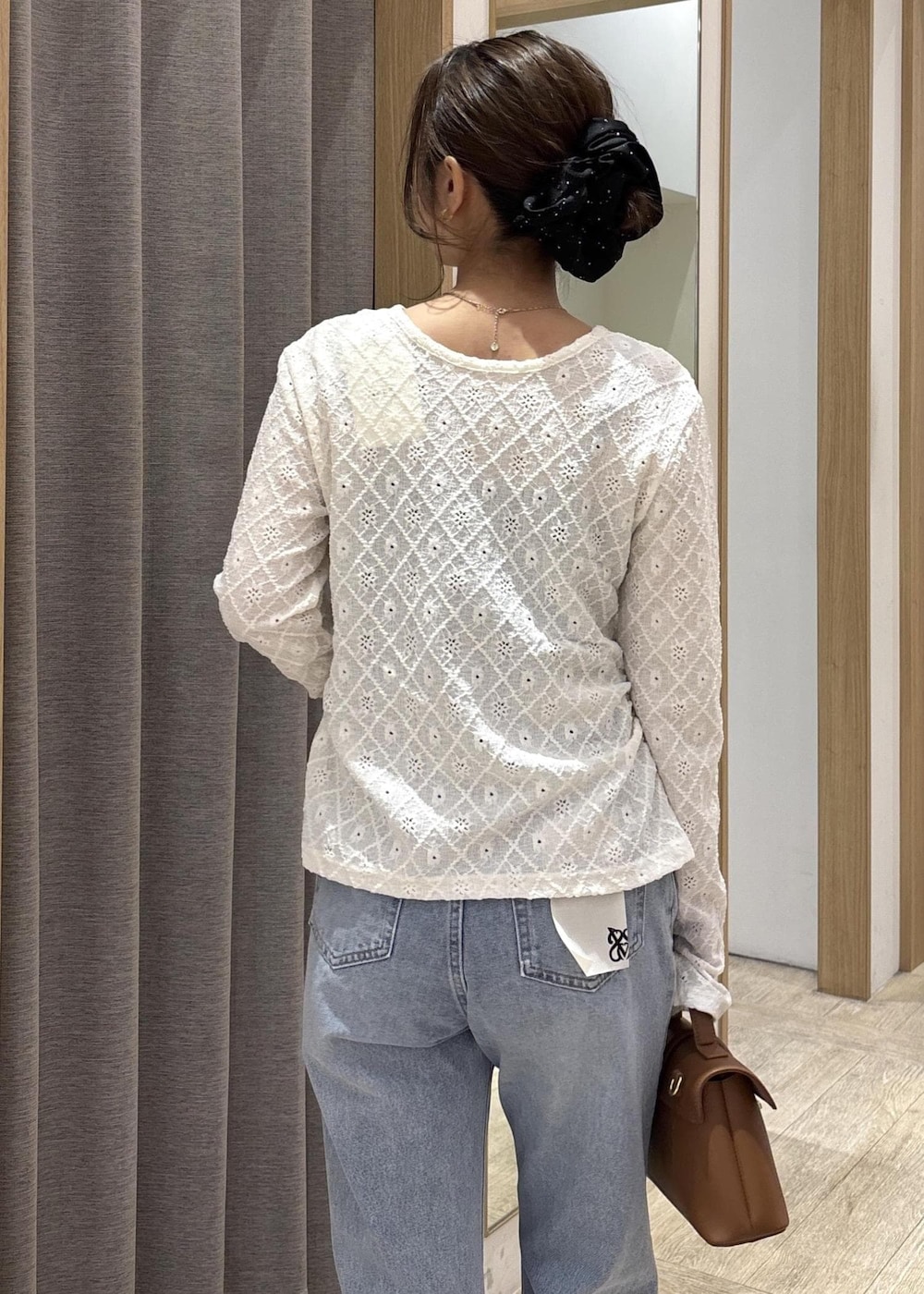 イエロー系のショルダーバッグ、ホワイト系のカーディガン/ボレロ、ブルー系のデニムパンツを着用したレディースの春コーディネートの8枚目の写真