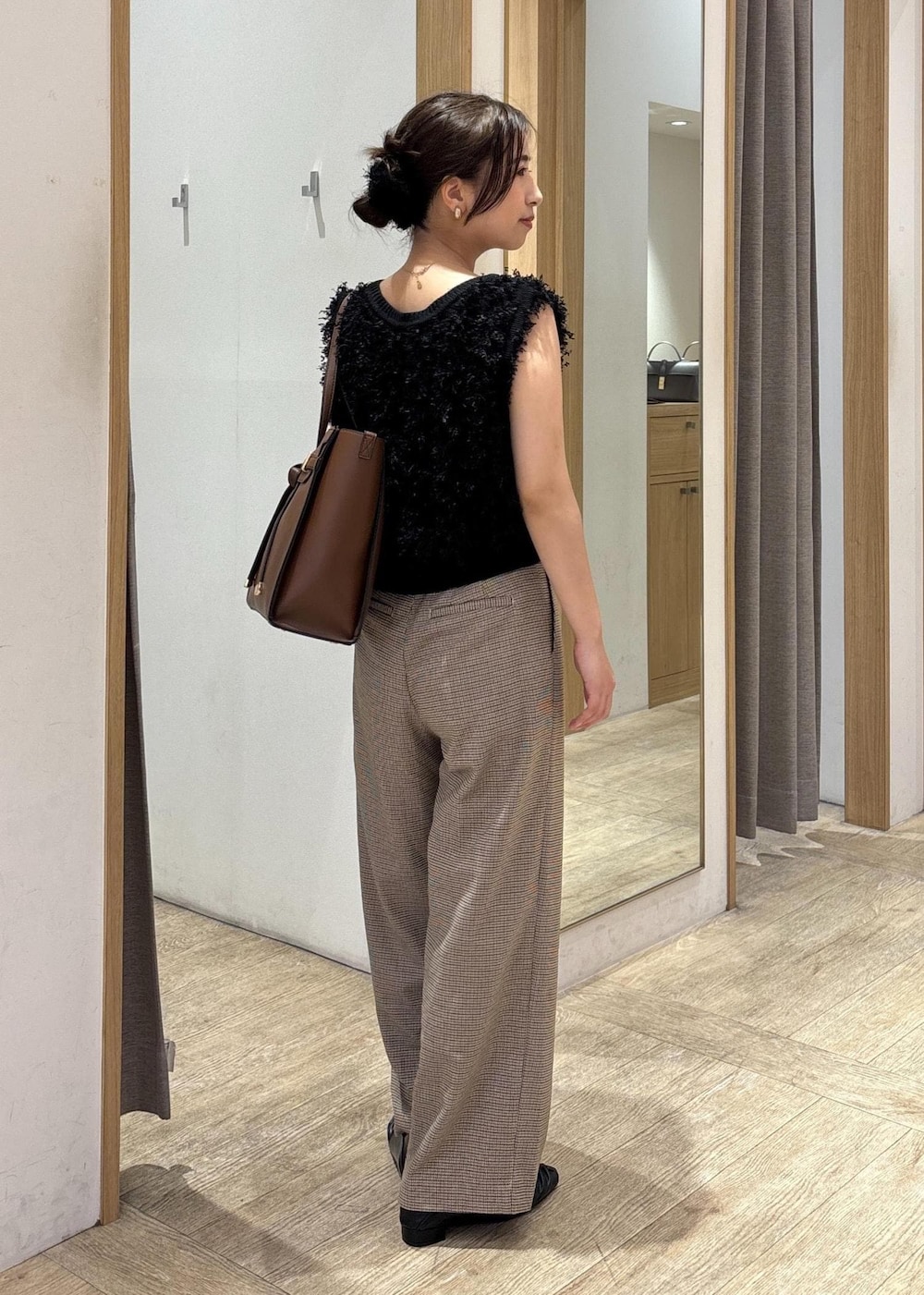 ブラック系のパンプス、ブラック系のベスト、ベージュ系のスラックスを着用したレディースの秋コーディネートの3枚目の写真