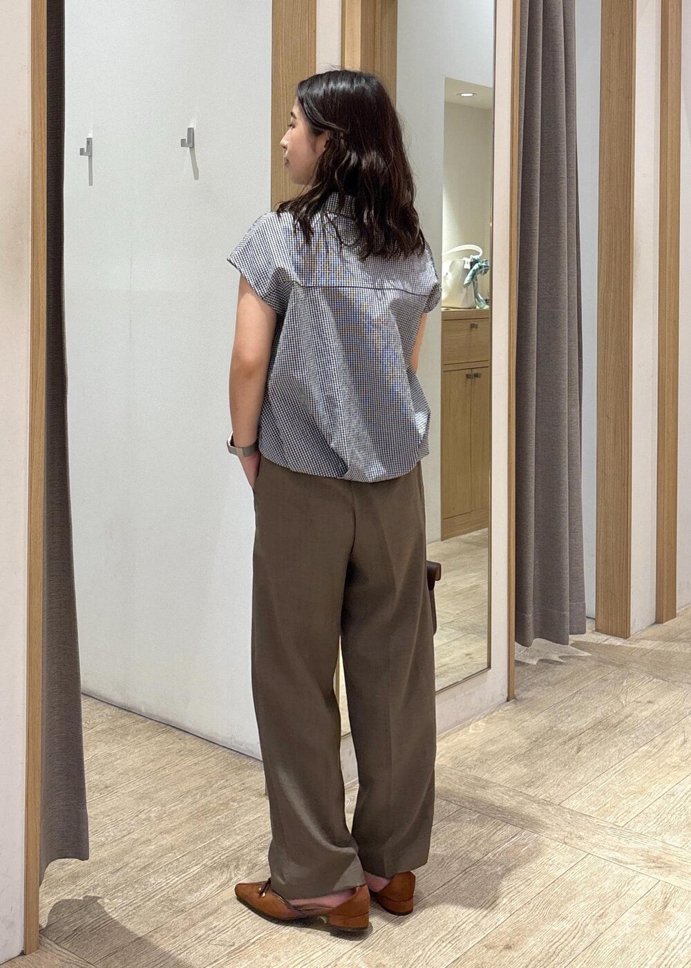 ブラウン系のショルダーバッグ、グリーン系のスラックス、ブラック系のシャツ/ブラウスを着用したレディースの夏コーディネートの3枚目の写真