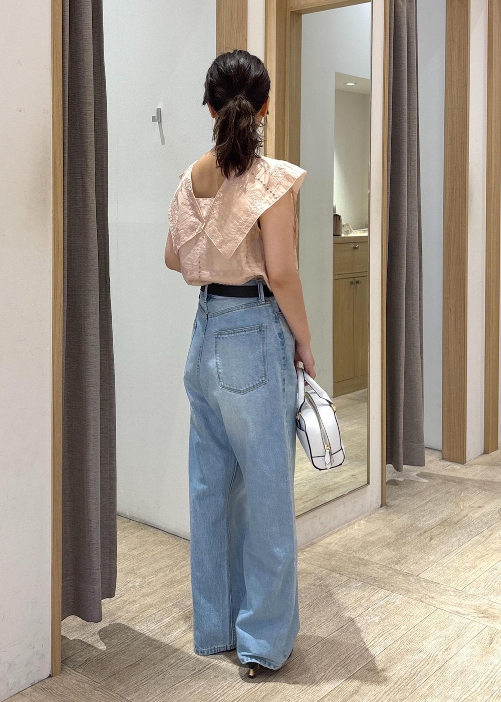 ブルー系のデニムパンツ、ブラック系のサンダル、ブラック系のショルダーバッグを着用したレディースの夏コーディネートの3枚目の写真